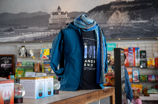 Blue jacket and black Lands End San Francisco t-shirt merchandised with San Francisco gifts against a historic photo of Cliff House