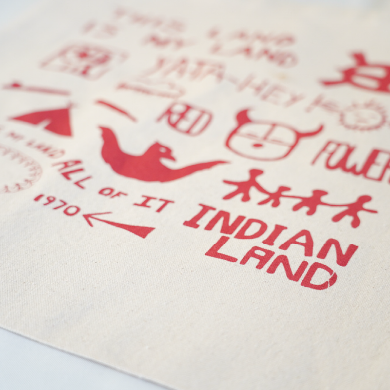Beige tote bag with red text and Alcatraz Occupation political statements on a white background
