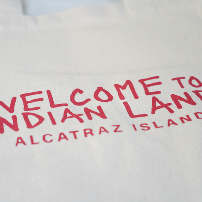 Beige tote bag with red text and Alcatraz Occupation political statements on a white background